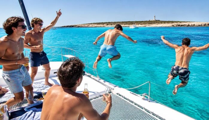 Amigos saltando al mar desde un catamarán en Formentera